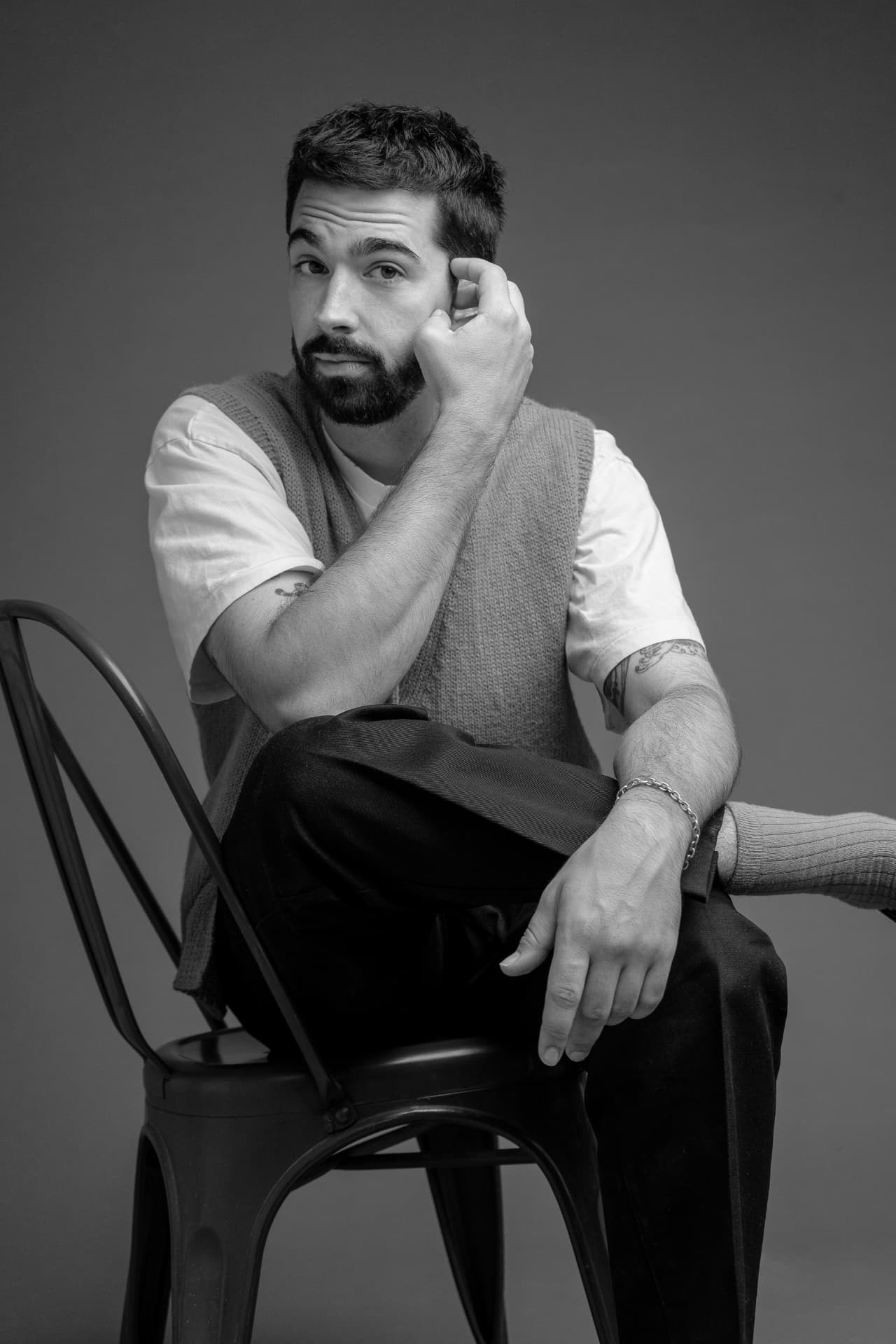 Black and white studio portrait of Alec Funiciello seated on a metal chair